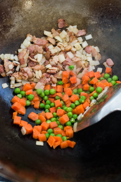 bacon, onion, peas and carrots in a wok