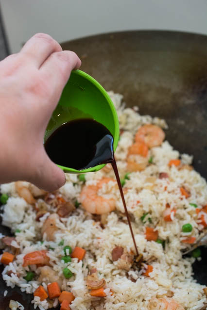 pouring soy sauce into fried rice in wok