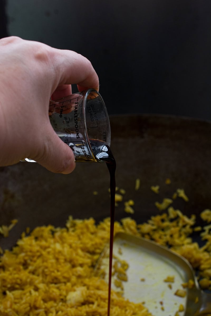 pouring soy sauce into a wok to season fried rice