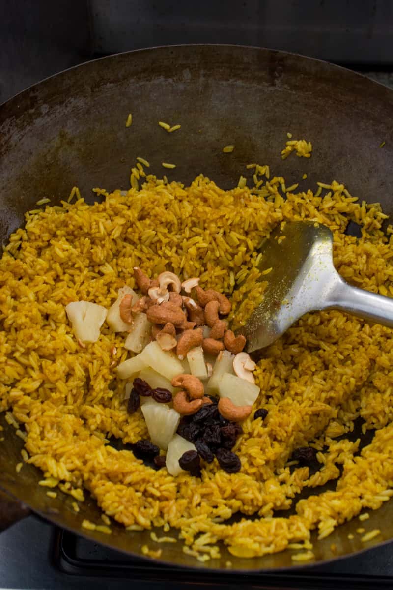 adding pineapple, cashews and raisins to pineapple fried rice