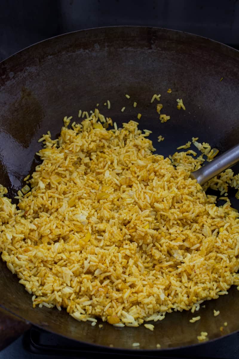 coating rice in buttered spices for pineapple fried rice