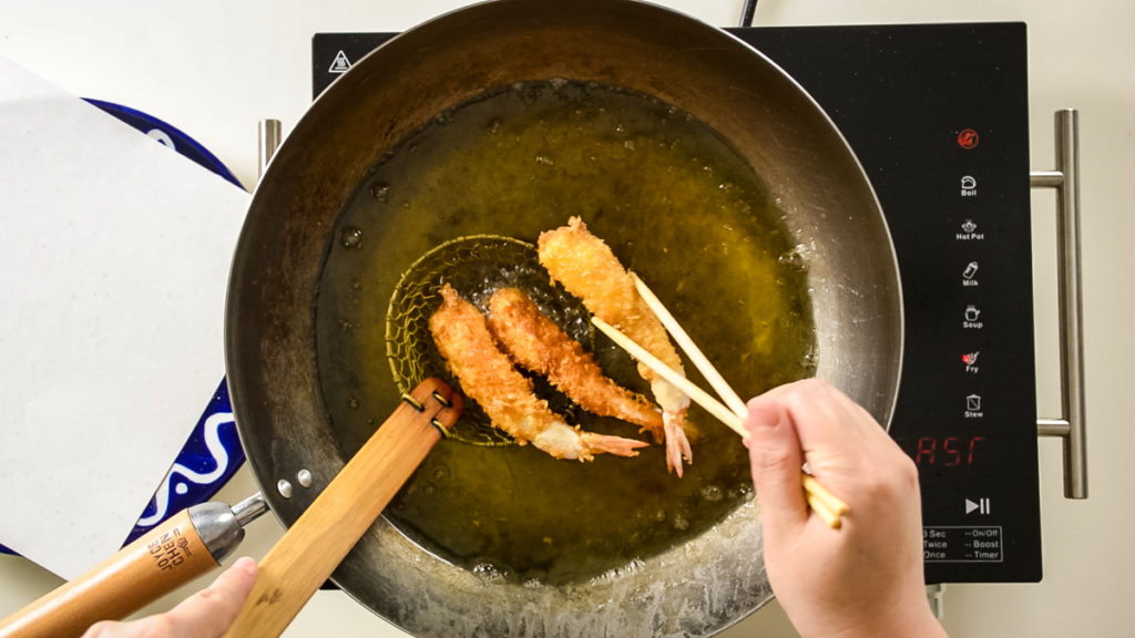 熱した油から海老の天ぷらを取り出す