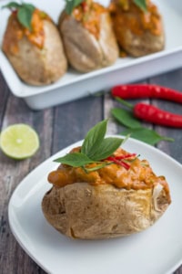 Thai Red Curry Baked Potatoes is an "East Meets West" version of comfort food. Perfect fluffy baked potato topped with a creamy, rich Thai Red Curry with tender chicken and crunchy green beans.