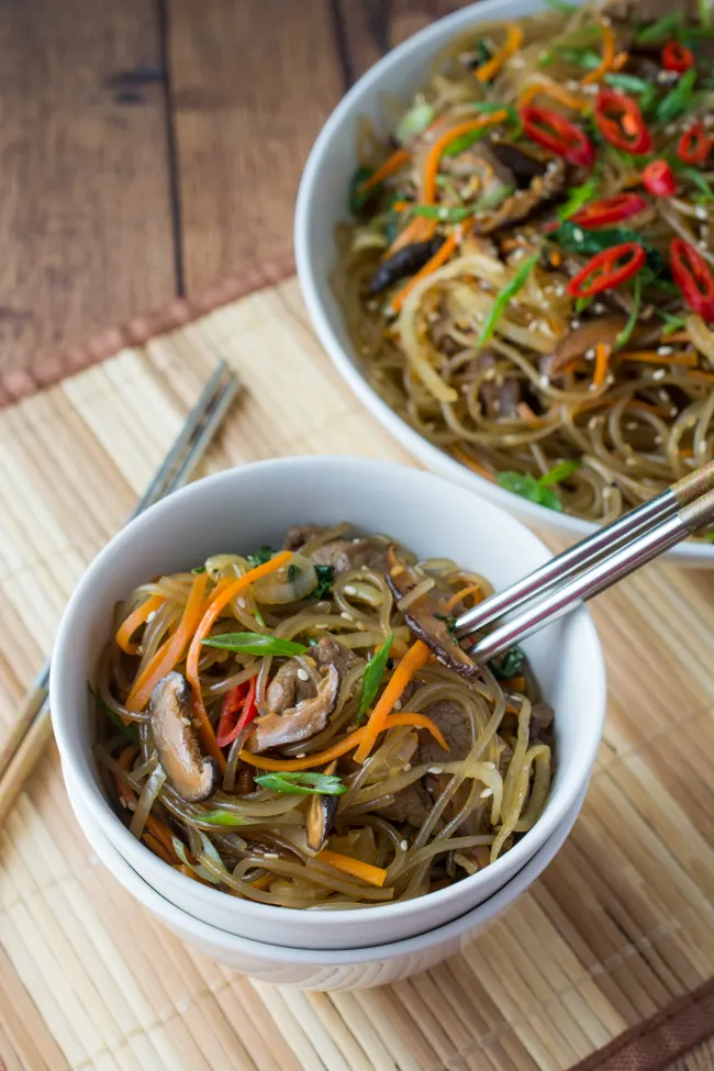 Japchae is a classic Korean noodle dish that can be served as a side dish, main dish, or over rice. Stir-fried glass noodles with sliced beef, julienned carrots, vegetables and mushrooms, tossed in a sweet soy sauce dressing.