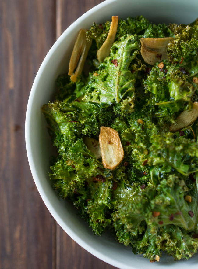 These healthy Spicy Garlic Kale Chips are irresistibly crispy and tasty! Fresh kale leaves are tossed in garlic oil and garlic powder, baked till crisp, then topped with crunchy garlic chips and spicy crushed red pepper. 