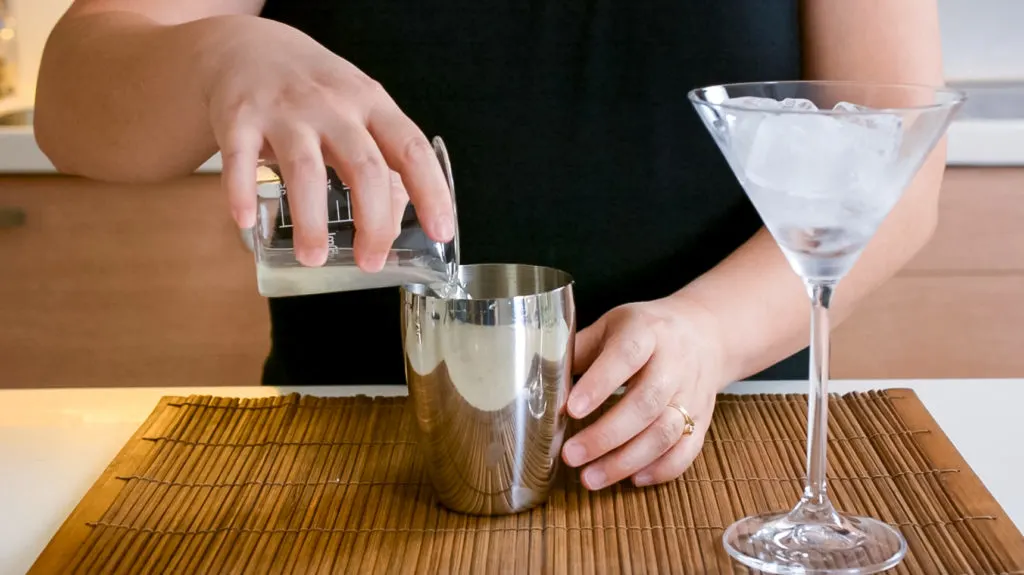 pouring lychee syrup into cocktail shaker for lychee martini