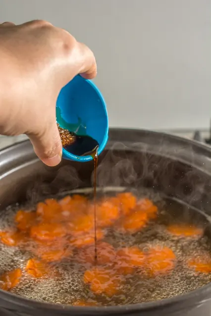 pouring soy sauce into boiling soup