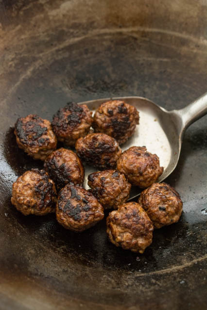 charred ground pork meatballs in a wok