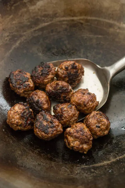 charred ground pork meatballs in a wok