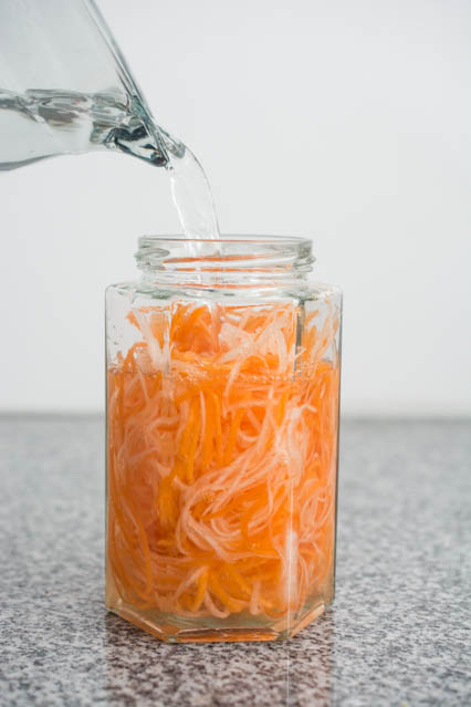 pouring vinegar in jar to make pickled carrot and daikon radish