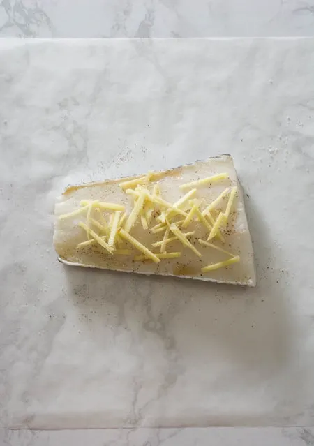 white fish fillet topped with ginger on parchment paper