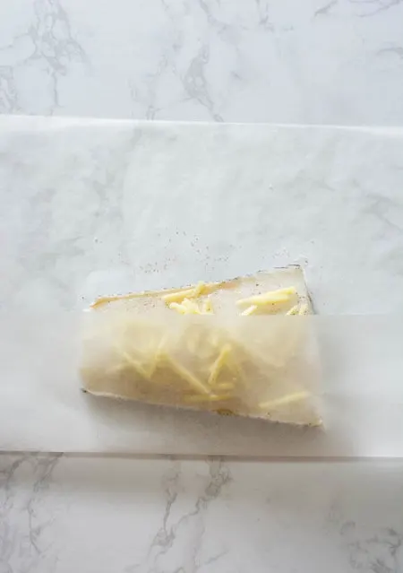 white fish fillet with ginger in folded parchment paper