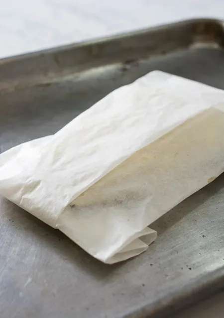 fish in folded parchment paper on baking tray