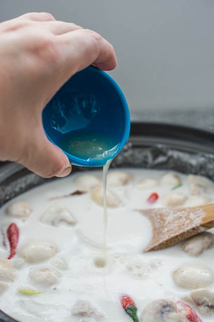 lime juice being poured into tom kha gai