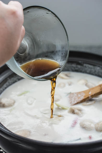 fish sauce being poured into tom kha gai
