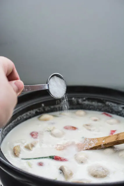 sugar being poured into tom kha gai soup