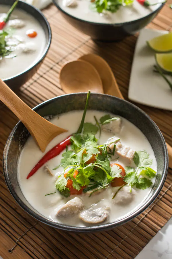 tom kha gai soup in a black bowl with wooden spoon