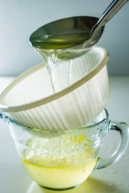 pouring chinese chicken stock through strainer