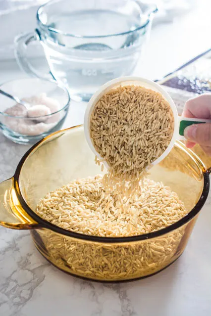 pouring uncooked brown rice from measuring cup