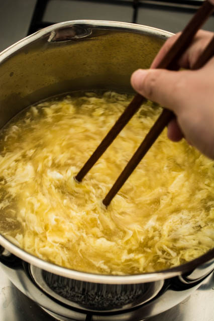 swirling egg drop soup with chopsticks