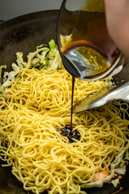 pouring sauce over noodles for Mie Goreng