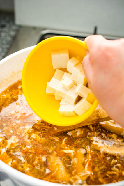 adding diced tofu to hot and sour soup