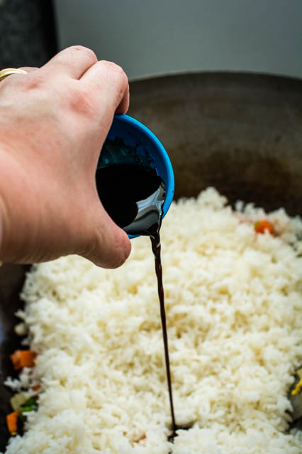 pouring soy sauce over rice for shrimp fried rice
