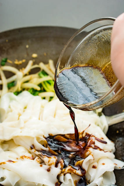 pouring sauce over beef chow fun