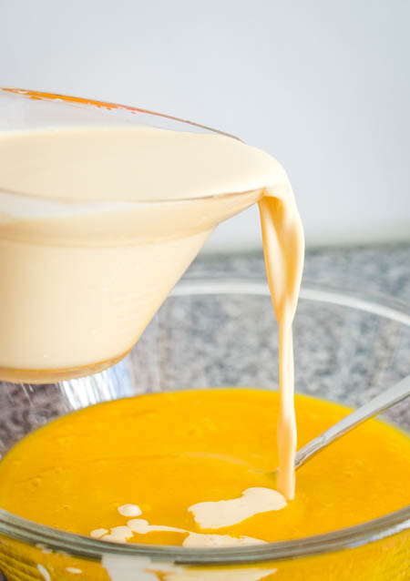 pouring evaporated milk in mango puree for chinese mango pudding