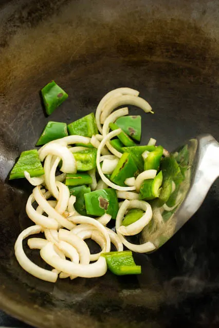 sliced onion and green bell pepper in a wok