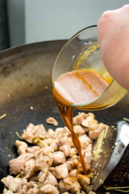 pouring sauce in wok to make cashew chicken