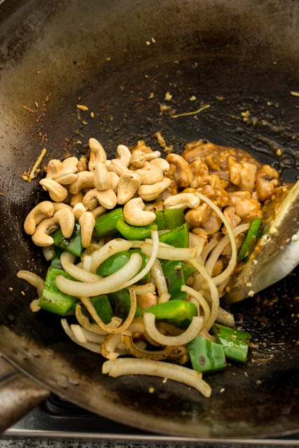roasted cashews, green bell pepper, onions and chicken in a wok