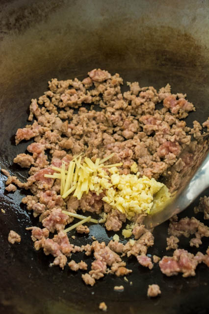 ground pork in a wok with garlic and ginger