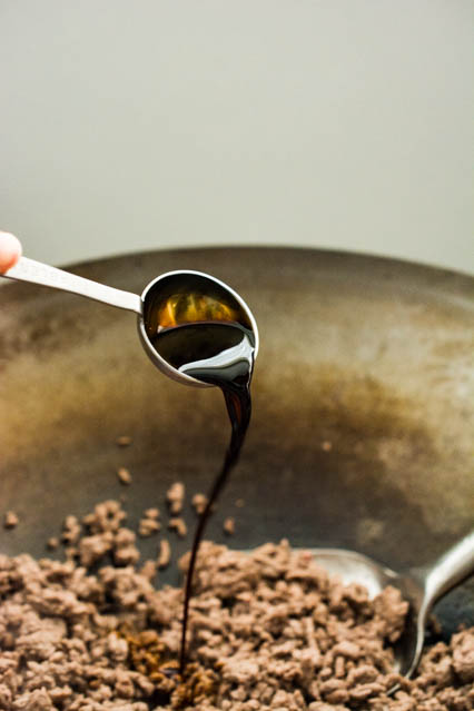 pouring soy sauce over ground beef for Korean Beef Bowls