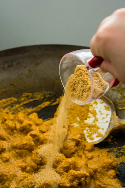 pouring brown sugar into red curry