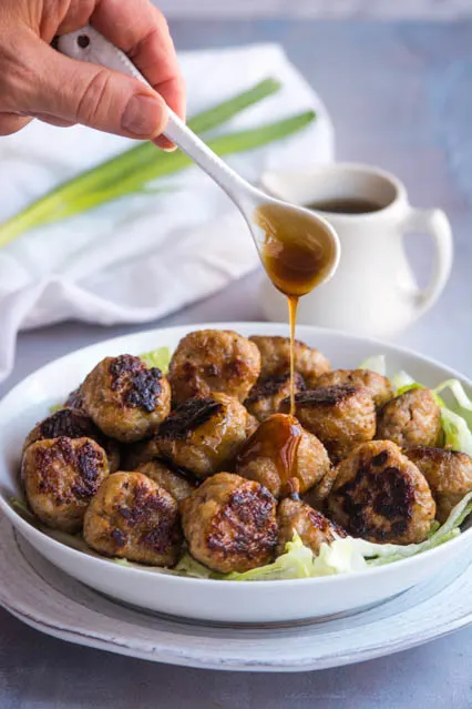 pouring sauce over Chinese BBQ meatballs