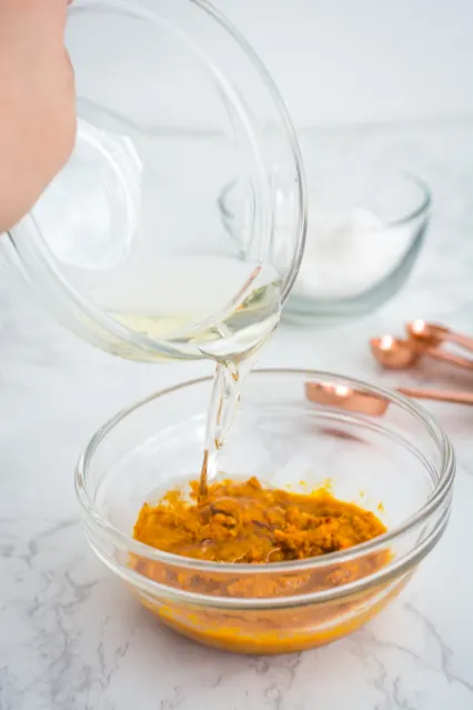 pouring coconut oil into thai yellow curry paste