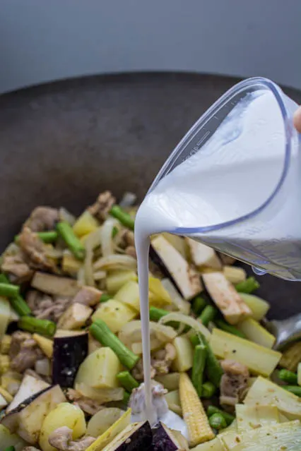 pouring coconut milk into green curry