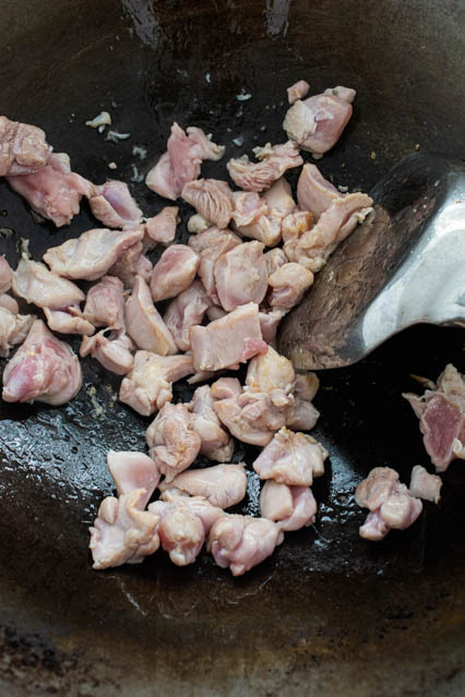 stirfry chicken in a wok for thai green curry