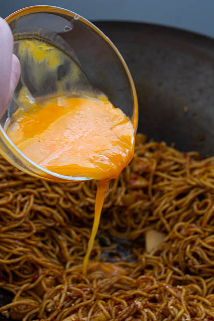 pouring egg into fried noodles