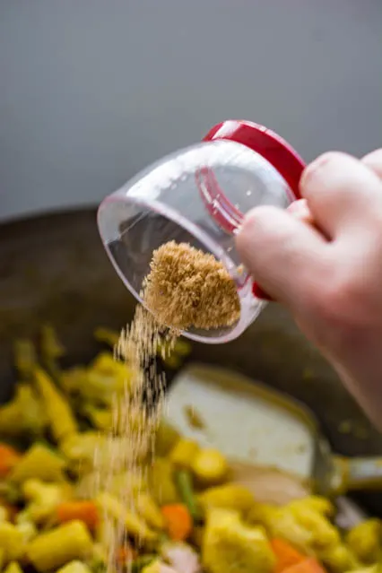 pouring brown sugar over vegetables