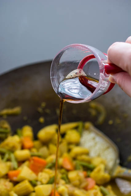 pouring fish sauce over vegetables