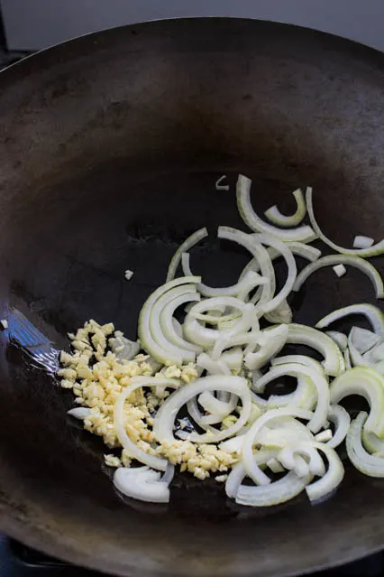 sliced and onions with minced garlic in a wok