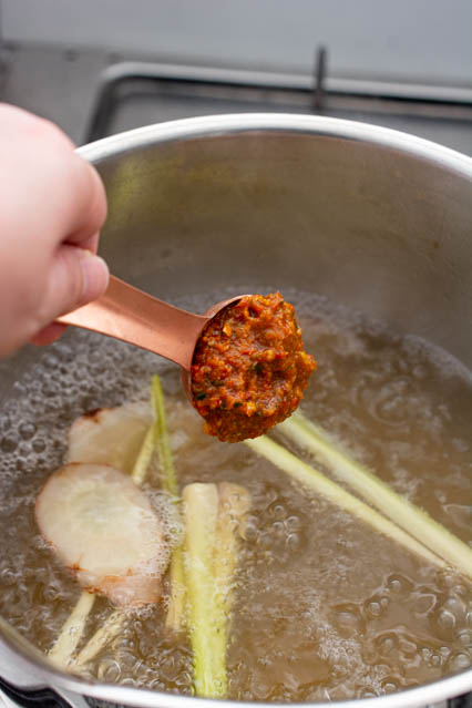 adding tom yum paste to chicken stock