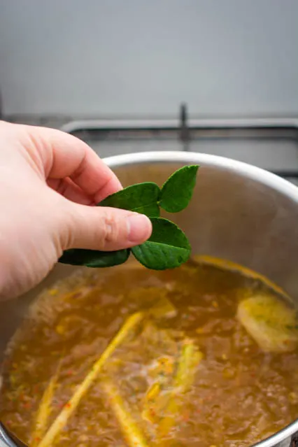 adding kaffir lime leaves to tom yum soup