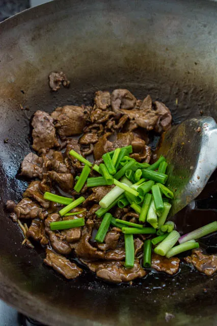 mongolian beef in a wok with scallions
