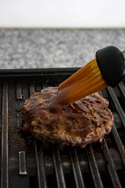 basting teritaki sauce on burger patty