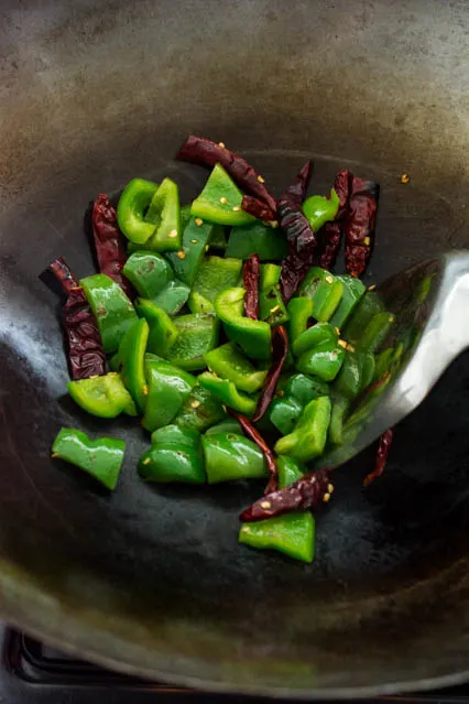 green bell pepper and dried red chili in a wok
