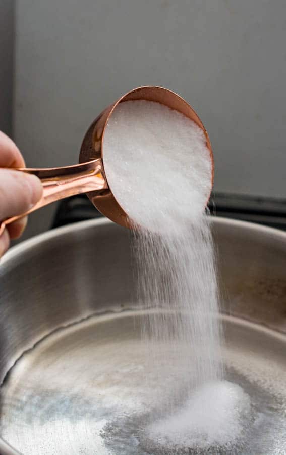 pouring sugar into to water in a saucepan