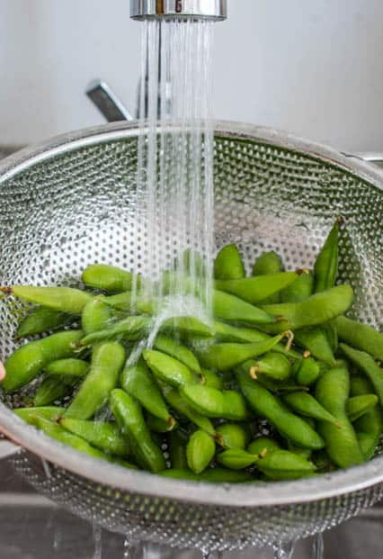 rinsing edamame under tap water